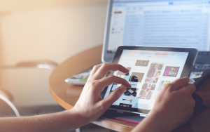 Person using an ipad with a computer in background